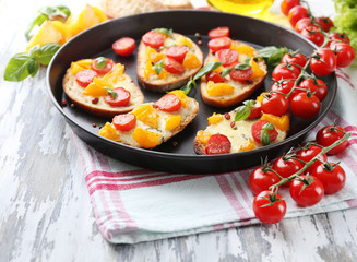 Tasty bruschetta with tomatoes on pan, on old wooden table