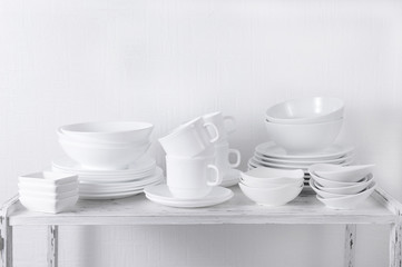 Set of white dishes on table on light background