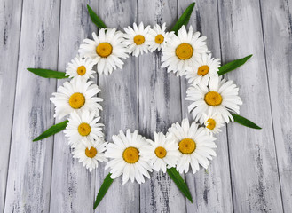 Obraz premium Chamomile wreath on grey wooden background