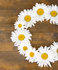 Chamomile wreath on brown wooden background