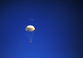 single parachute jumper against blue sky background