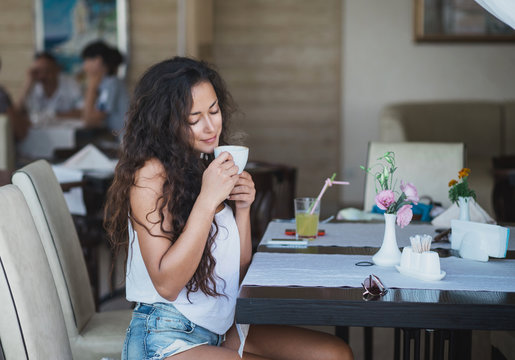 Young woman enjoying smell of coffee