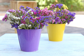 Beautiful flowers in flowerpot on wooden table, outdoors