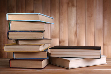 Books on wooden table on wooden wall background