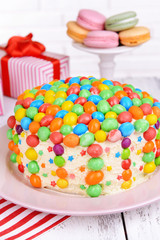 Delicious rainbow cake on plate on table on bright background