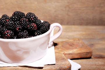 Sweet blackberries in color bowl on  wooden background