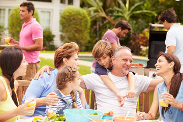 Multi Generation Family Enjoying Meal In Garden Together