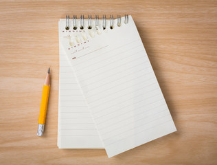 Note book with pencil on a wooden desk