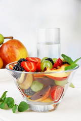 fresh tasty fruit salad on table, on light background