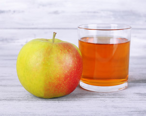 glass of apple juice and fresh apple on grey wooden table