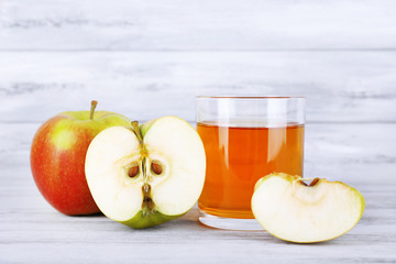 glass of apple juice and fresh apples on grey wooden table