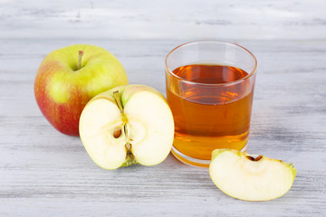 glass of apple juice and fresh apples on grey wooden table