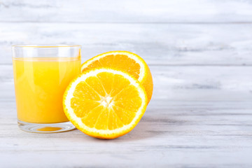 glass of juice with fresh orange on grey wooden table
