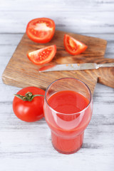 glass of tasty tomato juice and fresh tomatoes on wooden table