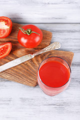 glass of tasty tomato juice and fresh tomatoes on wooden table