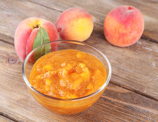 tasty peach jam with fresh peaches on wooden table