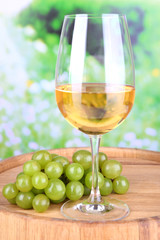 Tasty wine and ripe grape on green nature background
