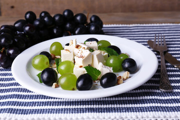 tasty salad with grape and cheese on wooden table