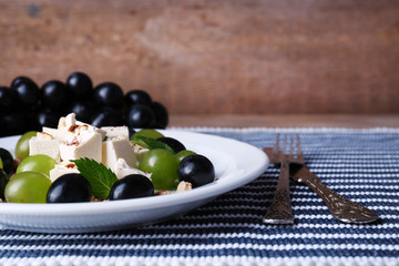 tasty salad with grape and cheese on wooden table