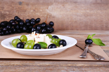 tasty salad with grape and cheese on wooden table