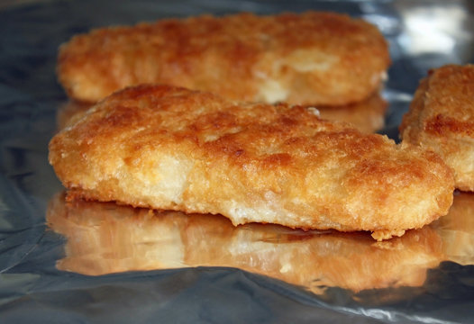 Breaded fish portions cooking on foil in the oven