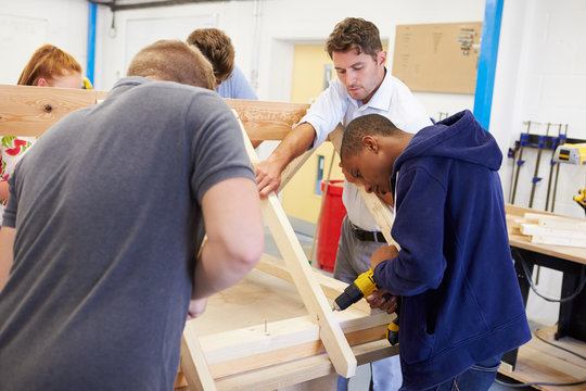 Teacher Helping College Students Studying Carpentry