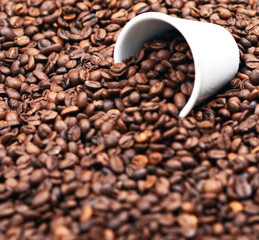 Cup of coffee filled with coffee beans against wooden background