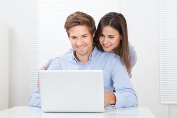 Fototapeta premium Surprised Man Looking At Woman While Using Laptop
