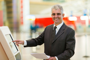 mature businessman using self help check in machine