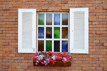 White window on red brick wall and color glass hang flowers pot.