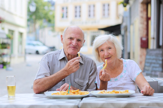 Happy Senior Couple Eating In Outdoors Cafe