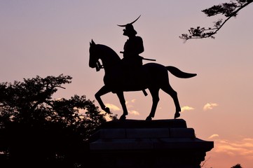 Naklejka premium 夕焼けの空に伊達政宗騎馬像