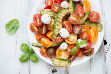 Salad with grilled avocado, tomatoes, mozzarella and green basil