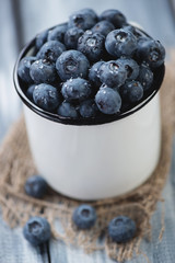 Close-up of an enameled cup with ripe blueberries, vertical shot