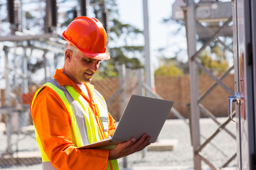 middle aged engineer using laptop in substation