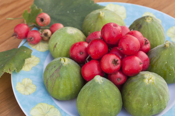 close up of composition of green figs and red azarolesin plate