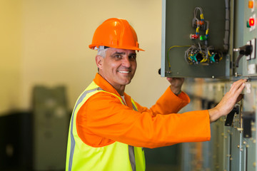 mid age electrician checking industrial control box