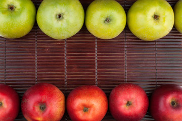 Green and red apples lie on the bamboo mat