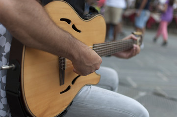 artista di strada con chitarra, con pubblico sullo sfondo