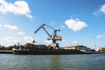 Fototapeta na wymiar Harbor - crane loading a ship with scrap metal