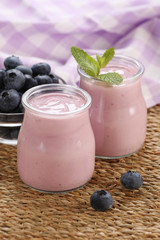 yogurt with blueberries in a glass jar and blueberries in a glas