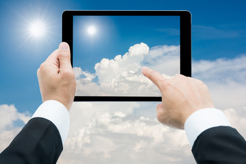 Businessman hands tablet taking pictures The sun and white cloud