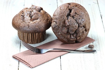 Schokoladenmuffins mit Gabel und Serviette auf Holztisch