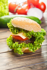 Cheeseburger with lettuce, onions and tomato in a sesame bun