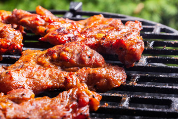 Grilling pork steaks on barbecue grill