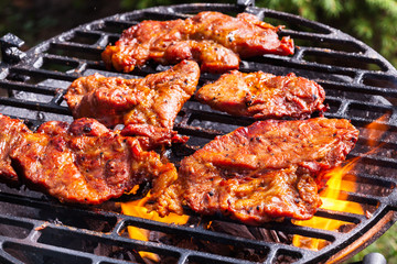 Grilling pork steaks on barbecue grill