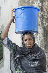 Afro beauty carrying a bucket of water in a slug - obrazy, fototapety, plakaty