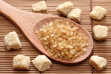 Brown cane sugar crystals in a wooden spoon