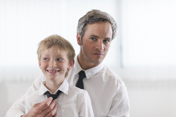 proud father helping his boy to put his tie