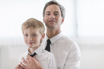 proud father helping his boy to put his tie